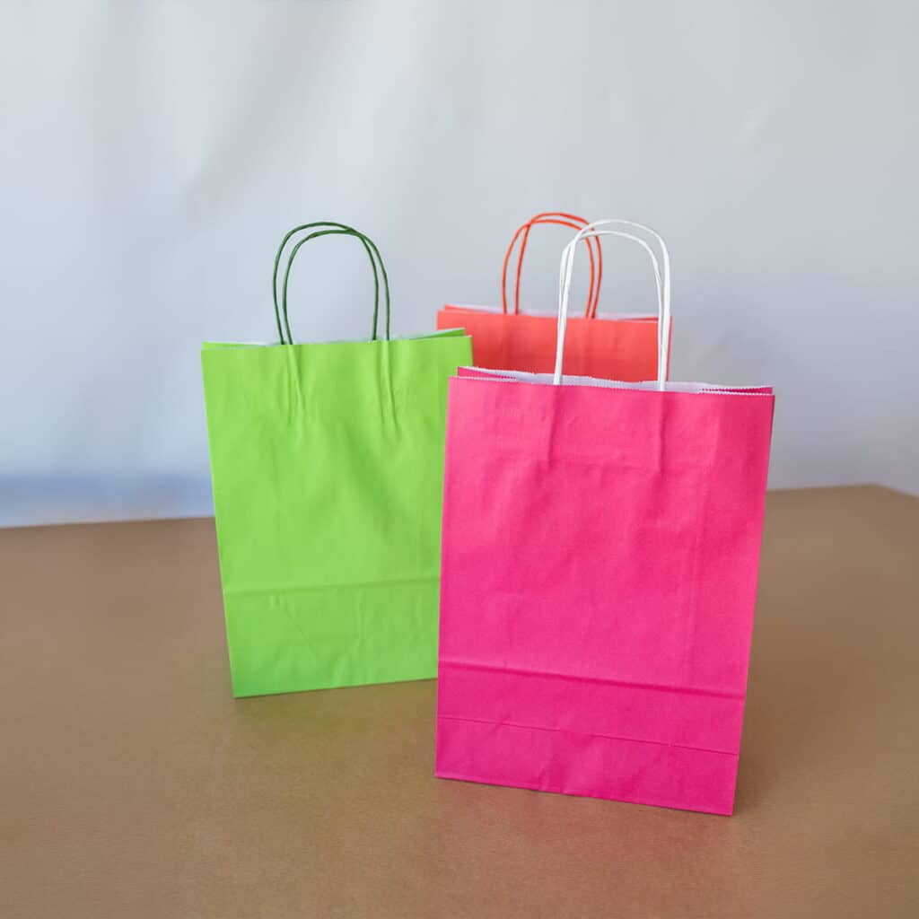 Gekleurde papieren draagtassen in roze, groen en rood met gedraaide handvatten – papieren tassen te bedrukken met eigen logo